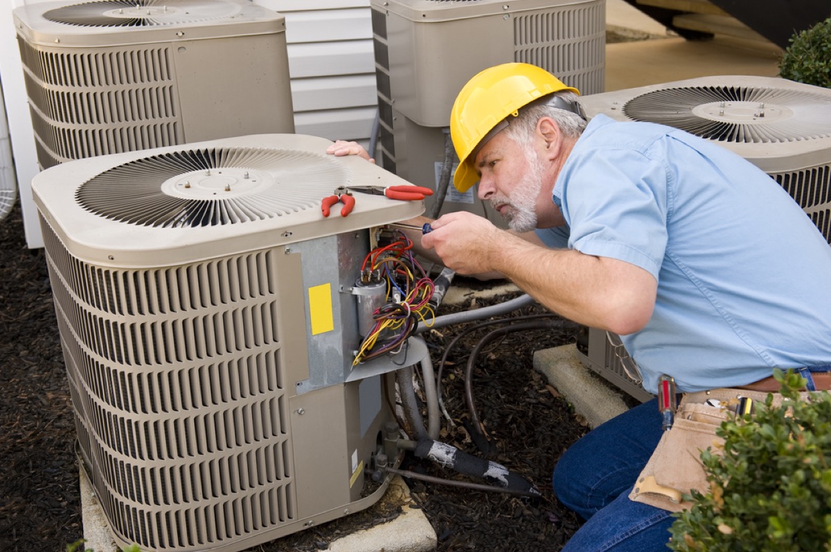 HVAC technician servicing an outdoor air conditioning unit