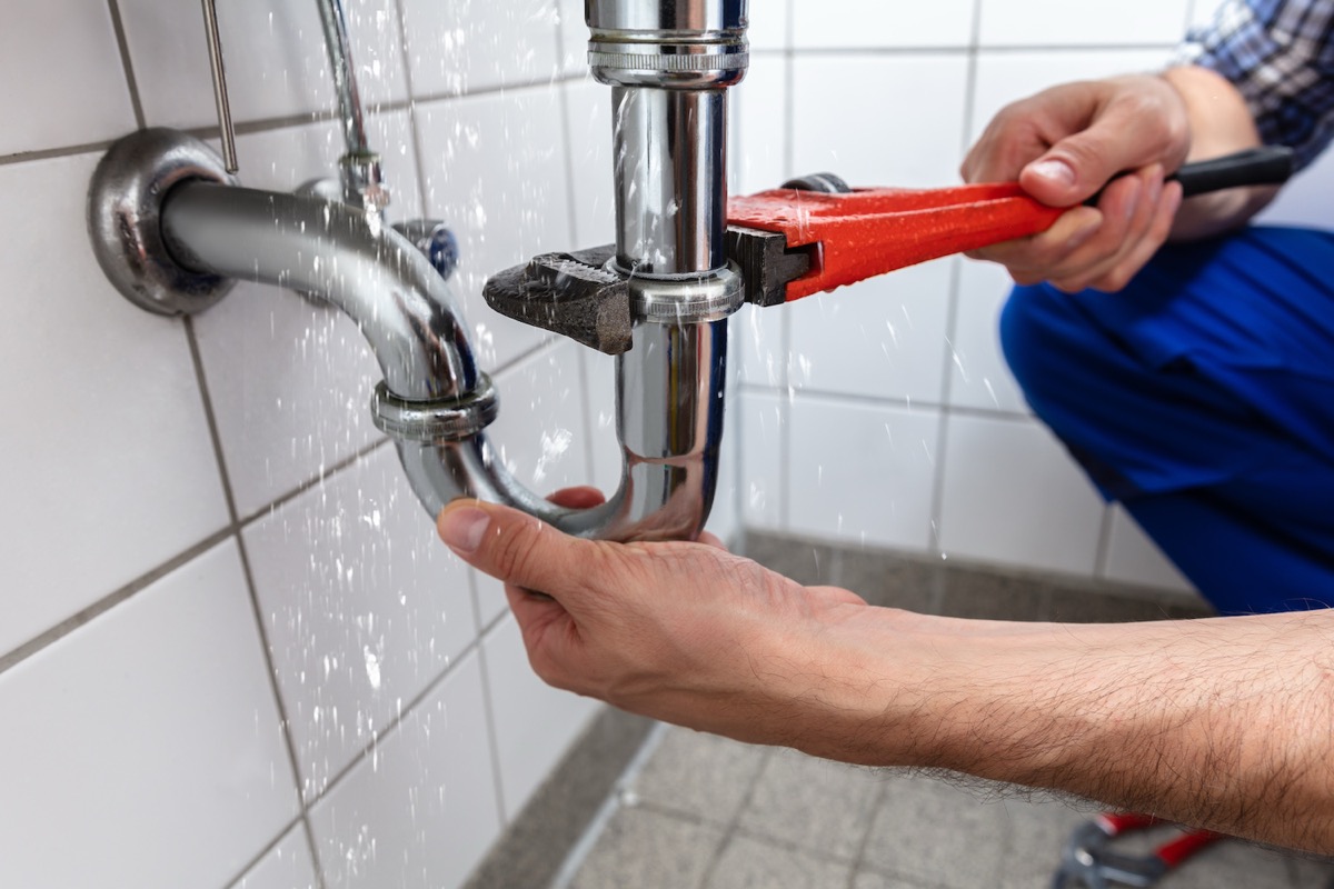 Plumber repairing pipes beneath a kitchen sink